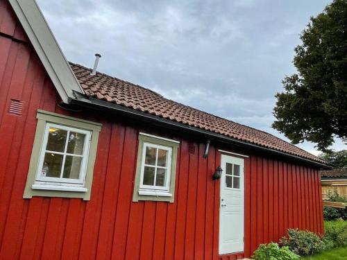 a red house with a white door and two windows at Apartament with access to garden, central, quiet and with free parking in Fredrikstad