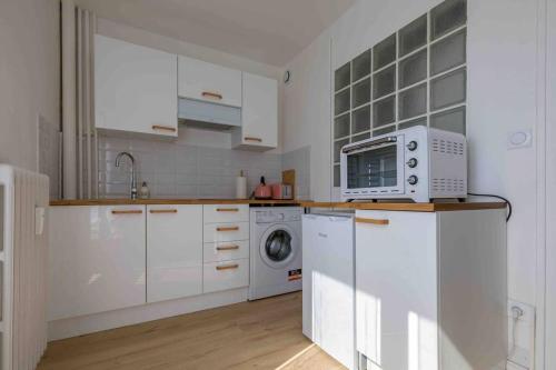 a kitchen with white cabinets and a washing machine at Le Cosy du Faux Bourg in Châlons-sur-Marne