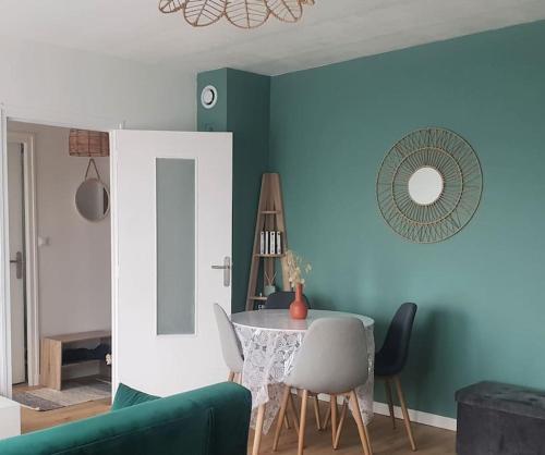 a living room with a table and a green wall at Le Cosy du Faux Bourg in Châlons-sur-Marne