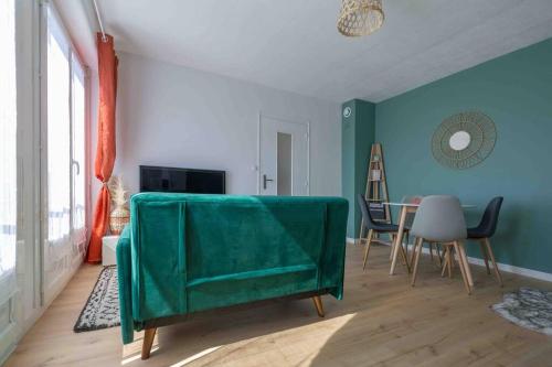 a living room with a green couch and a table at Le Cosy du Faux Bourg in Châlons-sur-Marne