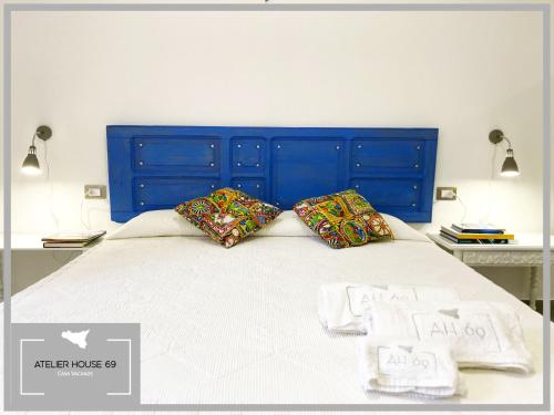 a bed with a blue headboard and pillows on it at Atelier House 69 in Trappeto