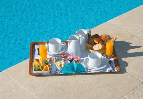 een dienblad met ontbijtproducten naast een zwembad bij Hotel La Garbine in Saint-Tropez