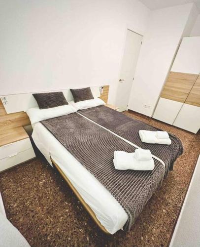 a bedroom with a large bed with two white shoes on it at Citadella Apartment in Puerto de Sagunto