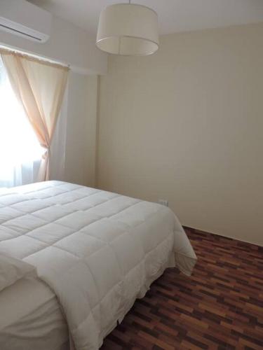 1 cama blanca en un dormitorio con ventana en Precioso departamento de dos ambientes Paraguay y Junin en Buenos Aires