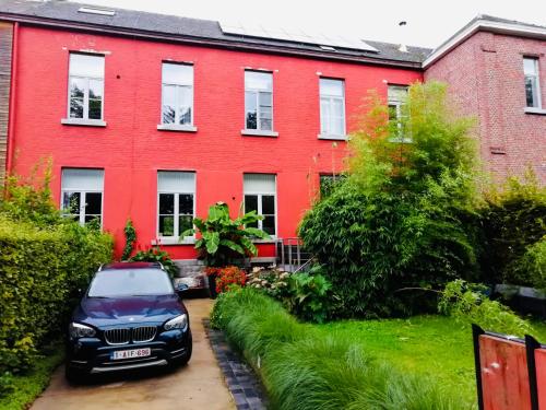a red house with a car parked in front of it at The Séroule Park House in Verviers