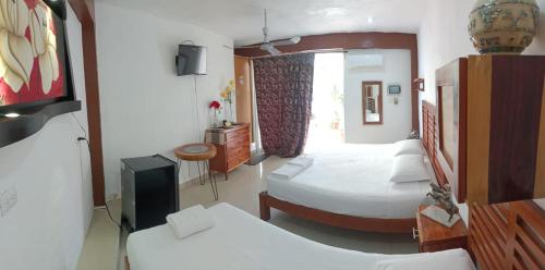 a hotel room with two beds and a television at Casa ka'an in Isla Mujeres