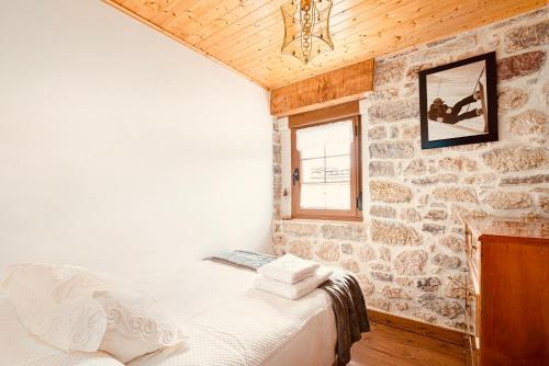 a bedroom with a bed and a stone wall at Villabu Babia in San Emiliano
