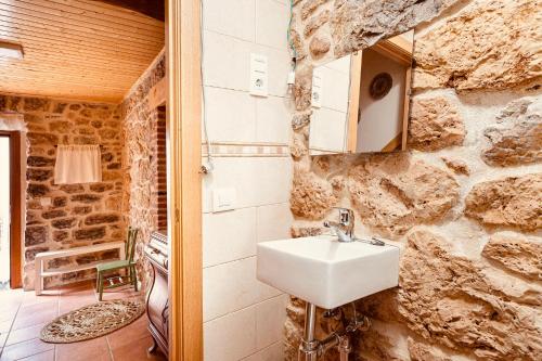 uma casa de banho com um lavatório numa parede de pedra em Villabu VUT-LE-736 em San Emiliano