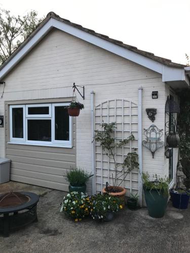 a garage with potted plants on the side of it at Annexe in lymington with private use of hot tub in Everton