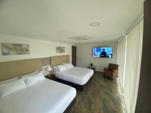 a hotel room with two beds and a flat screen tv at Hotel Explore Caño Dulce in Tubará