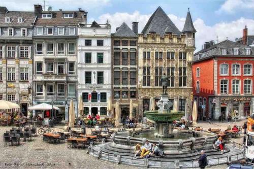 a fountain in the middle of a city with buildings at Modernes Apartment mit 75qm mit Balkon & Aussicht in Aachen