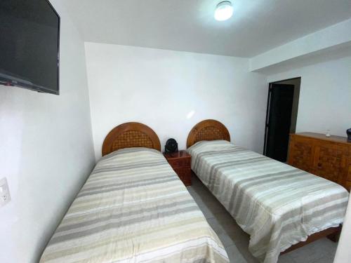 two beds in a room with a flat screen tv at Casa Tenorio Hospedaje in Orizaba