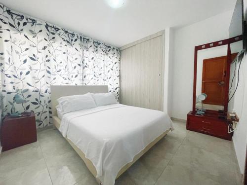 1 dormitorio con cama blanca y papel pintado con motivos florales en frente al mar en Cartagena, en Cartagena de Indias