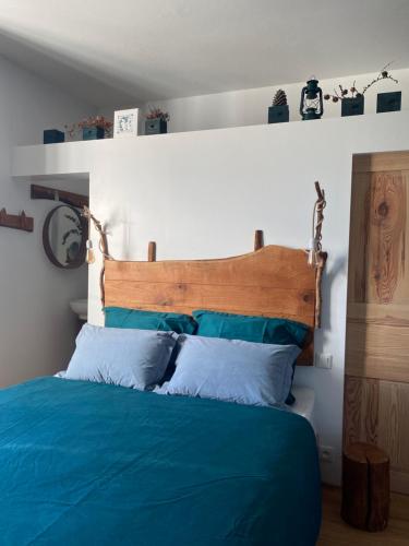 a bedroom with a blue bed with a wooden headboard at La Vieille Eglise in Le Hohwald