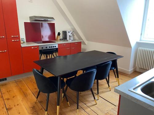 a black table and chairs in a kitchen with red cabinets at MannheimMitte Zimmer3 Denkmalschutz Stadthaus - 2 Personen in Mannheim