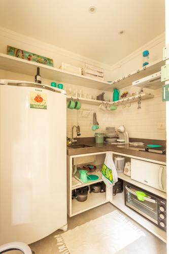 a kitchen with a white refrigerator in a room at Casa d'Aroeira Residencial Boutique - Centro de Juqueí - 2 quadras do mar - Serviço de Praia - Roupa de Cama 600 fios algodão Egípcio - Toalhas Banho e Praia - Tudo Novo - Estacionamento Interno - Cozinha - Consulte unidades com Ofurô Hidro e Cromoterapia in Juquei