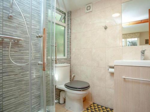 a bathroom with a toilet and a glass shower at Aremo Garden House in Torquay
