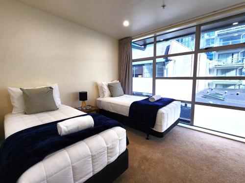 a bedroom with two beds and a large window at U Suites on Jessie in Wellington