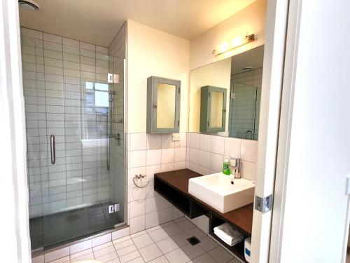 La salle de bains blanche est pourvue d'un lavabo et d'une douche. dans l'établissement U Suites on Jessie, à Wellington