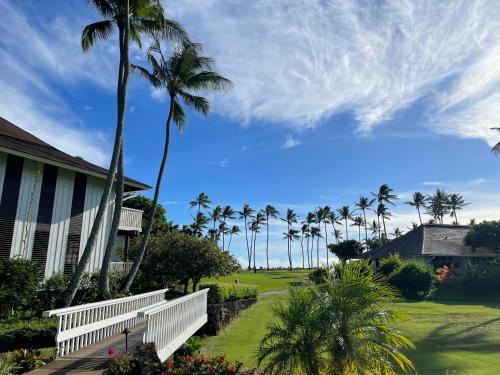 a house with palm trees and a white fence at Kiahuna Plantation Unit 42, Air Conditioning, 2 Minute Walk to Beach in Koloa