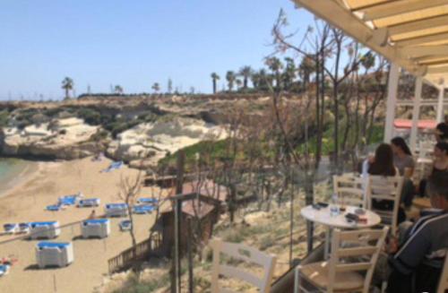 a group of people sitting at a table near a beach at Anastasia Waterpark Beach Resort in Protaras
