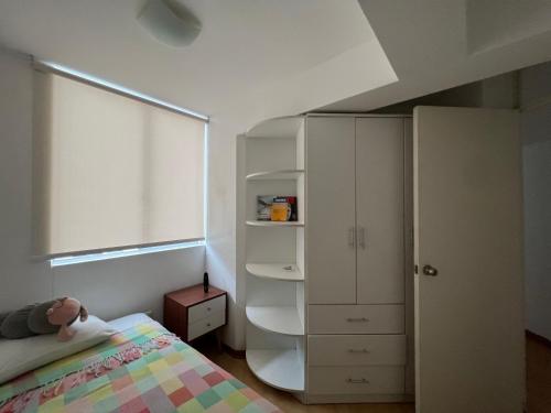 um quarto com uma cama e um armário branco em Acogedor y espacioso apartamento em Lima