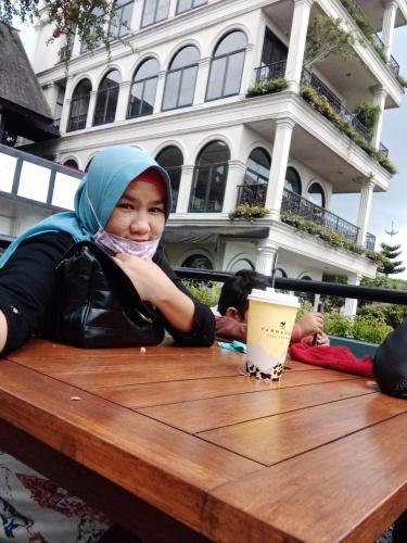 uma mulher sentada à mesa com uma chávena de café em Apartment em Bandung