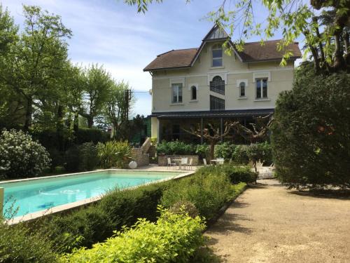 una casa con piscina frente a una casa en Hôtel de charme L'Orée du Parc, en Romans-sur-Isère