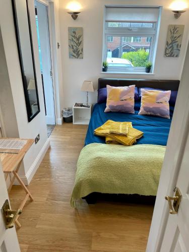 1 dormitorio con cama con sábanas azules y ventana en Boscote en Stratford-upon-Avon