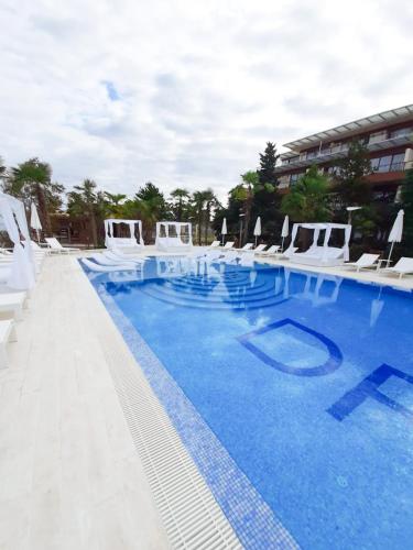 a large swimming pool with white chairs and a building at Luxury Dreamland Oasis Apartments in Chakvi
