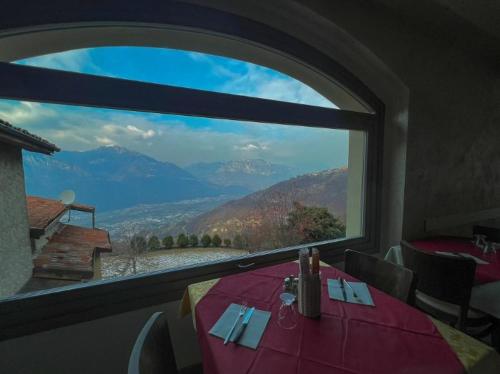 a table with a view of a mountain from a window at Osteria Carli B&B in Gratacasolo
