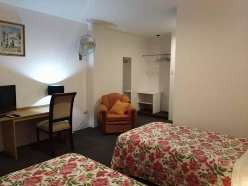 a hotel room with a bed and a chair and a desk at Hotel La Posada Del Ingles in Chiclayo