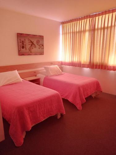 a hotel room with two beds with red sheets at Hotel La Posada Del Ingles in Chiclayo