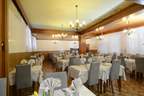 una sala banchetti con tavoli e sedie bianchi e lampadari a braccio di Hotel Vittoria a Levico Terme