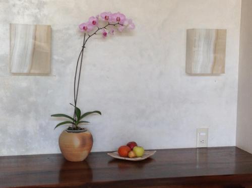 a vase with a flower and a bowl of fruit at Casa Flor de Mar in Zipolite