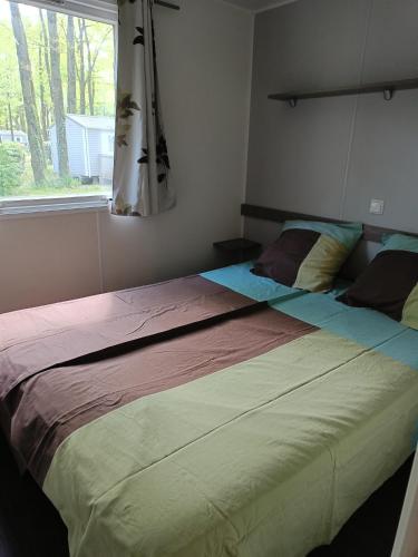un grand lit dans une chambre avec une fenêtre dans l'établissement Mobilhome climatisé 3 chambres à 30 min du Puy du F et de Nantes, à La Boissière-de-Montaigu