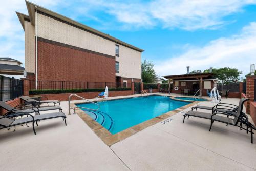 a swimming pool with two chairs next to a building at Best Western Plus Lake Dallas Inn & Suites in Lake Dallas