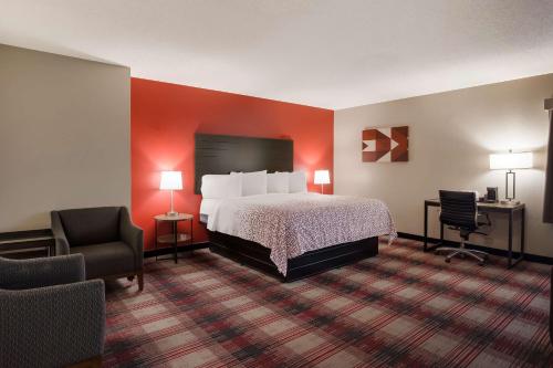 een hotelkamer met een bed en twee stoelen bij SureStay Hotel by Best Western Higginsville in Higginsville