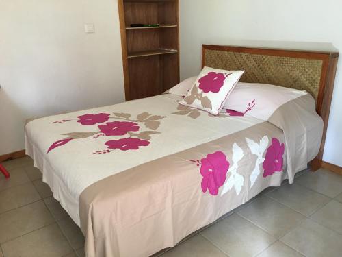 a bedroom with a bed with pink flowers on it at Pension Te Aroha - Te Rai in Maatea