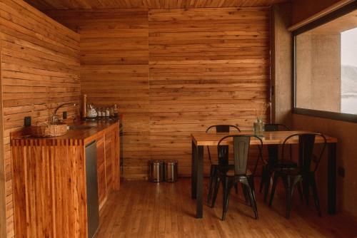 La Calma Ecolodge في Las Heras: غرفة طعام بجدران خشبية وطاولتين وكراسي