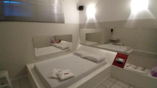 a white bathroom with two mirrors and a tub at Lagos Suítes in Guapé