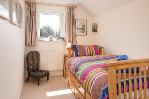 a bedroom with a bed and a chair and a window at Coldstream Coach House in Coldstream