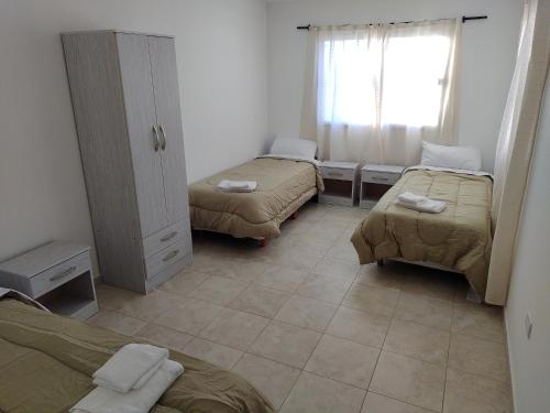 a small room with two beds and a window at Duplex Escritores Argentinos in Rawson