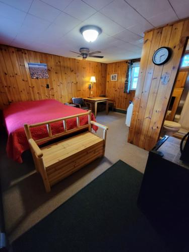 ein Schlafzimmer mit einem Bett in einem Zimmer mit Holzwänden in der Unterkunft Two Rivers Motel and Cabins 