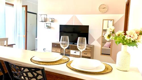 a dining table with two glasses and a vase of flowers at Eleonora Home in Porto Torres