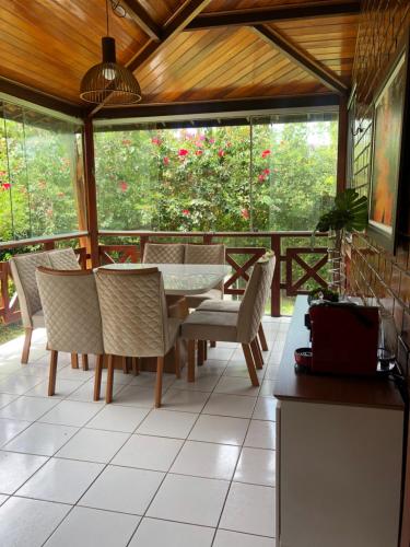 a dining room with a table and chairs on a porch at Bangalô Doce lar in Gravatá