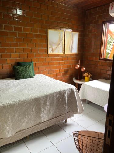 a bedroom with a bed and a brick wall at Bangalô Doce lar in Gravatá