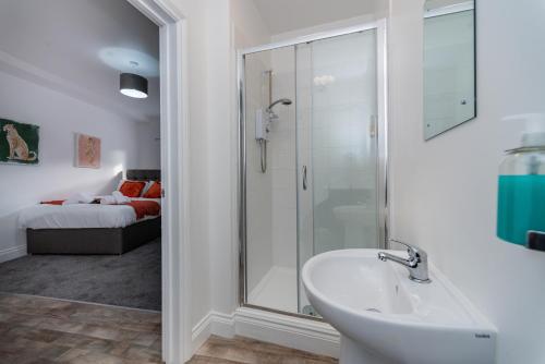 ein Bad mit einem Waschbecken und einer Glasdusche in der Unterkunft Croft Road Apartments in Neath