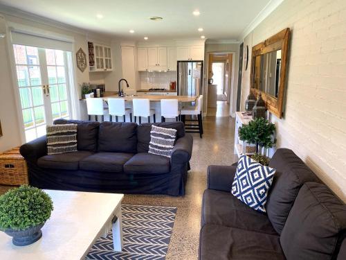 Una sala de estar con dos sofás y una cocina. en The Edward Townhouses 151 & 153, en Orange