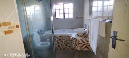 a bathroom with a tub and a toilet and a sink at Sthembile's guest house in Richards Bay